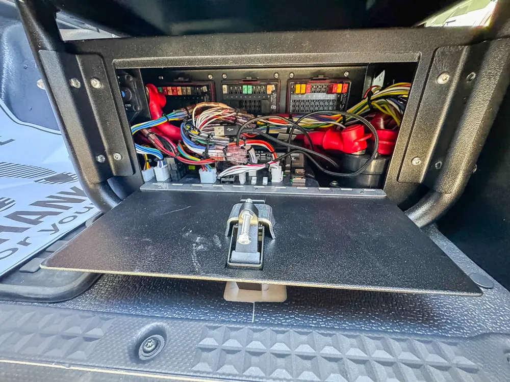 Open floor compartment with visible battery and electrical wiring.