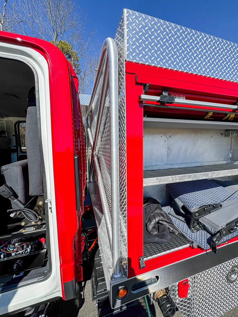 Open side body compartment beneath red hose bed cover.