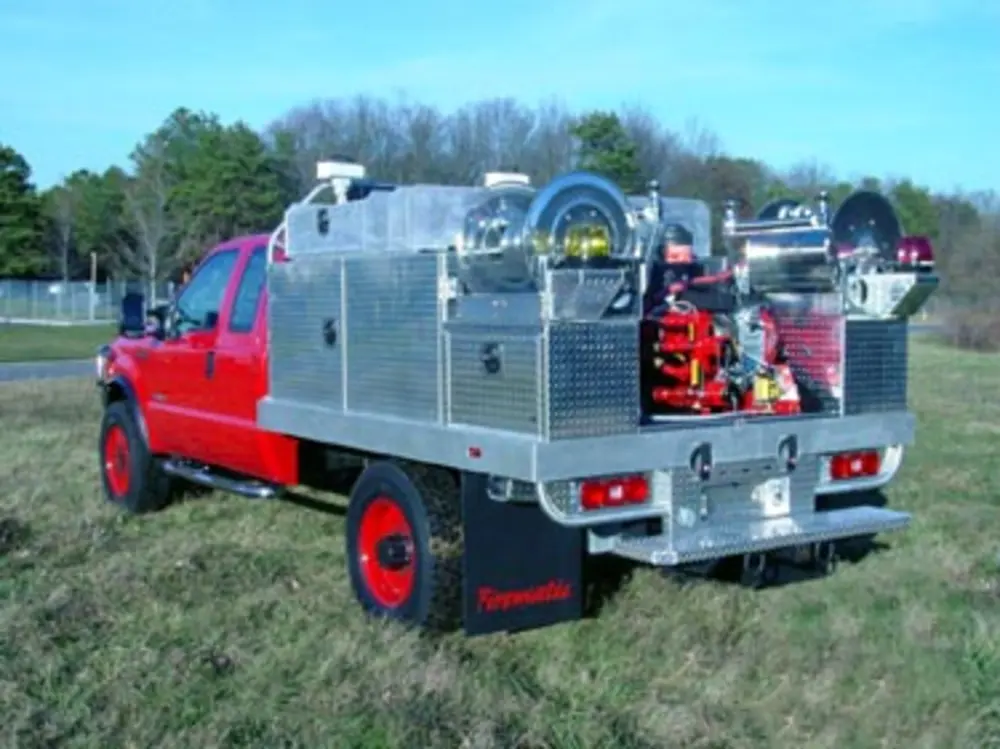 Exterior view of small fire truck showing cab, body compartments, and wheel/tire area.