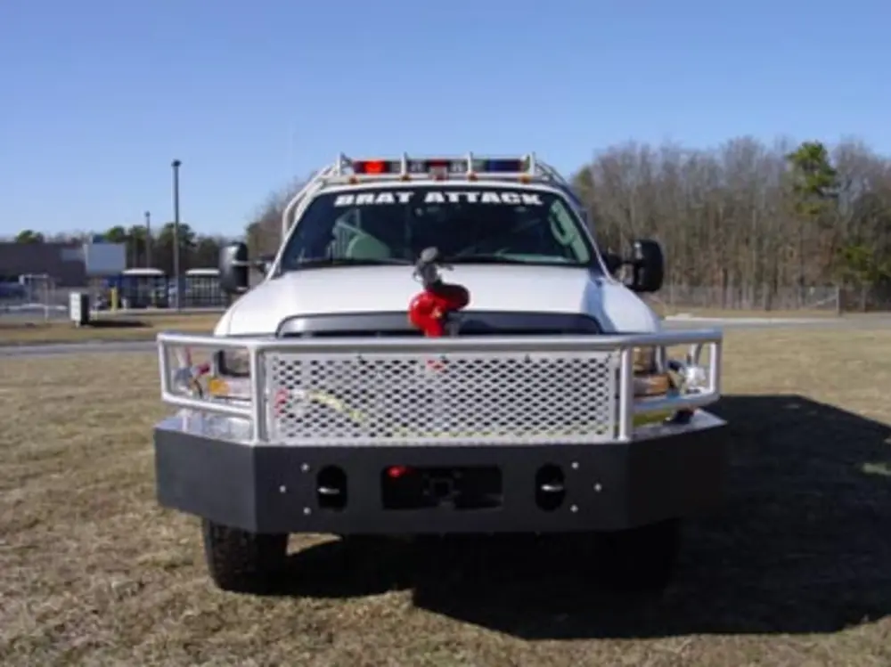 Exterior view of small fire truck showing cab, body compartments, and wheel/tire area.