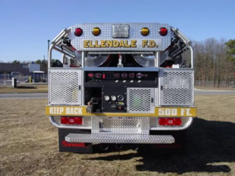 Exterior view of small fire truck showing cab, body compartments, and wheel/tire area.