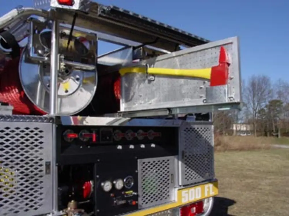 Exterior view of small fire truck showing cab, body compartments, and wheel/tire area.