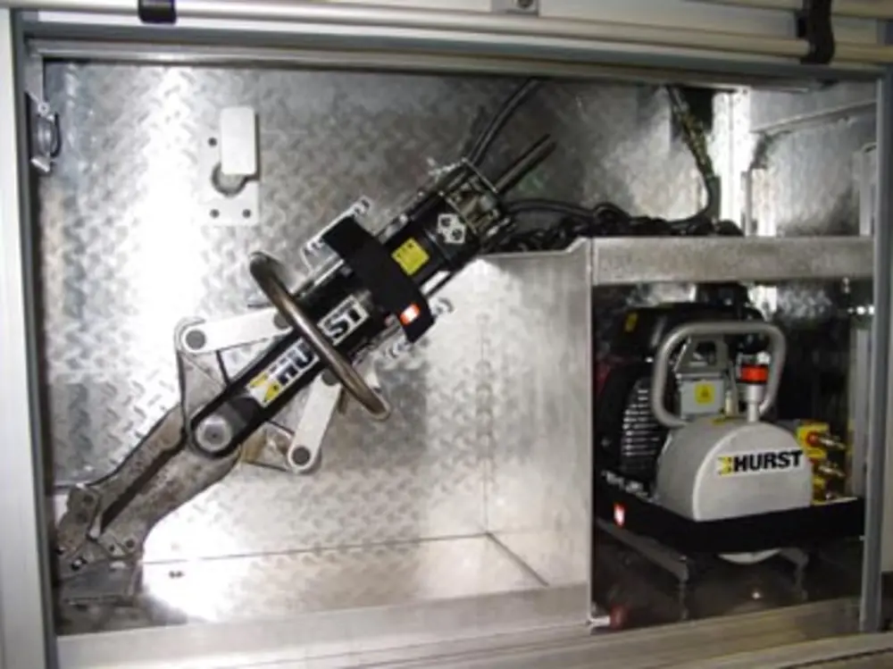 Exterior view of small fire truck showing cab, body compartments, and wheel/tire area.