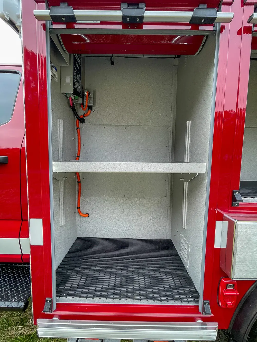 Open compartment interior with white shelves and wiring loom.