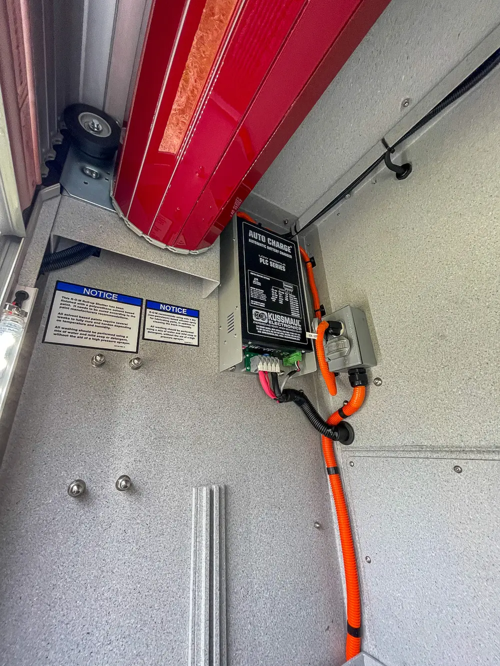 Compartment wall close-up with battery charger and labels.