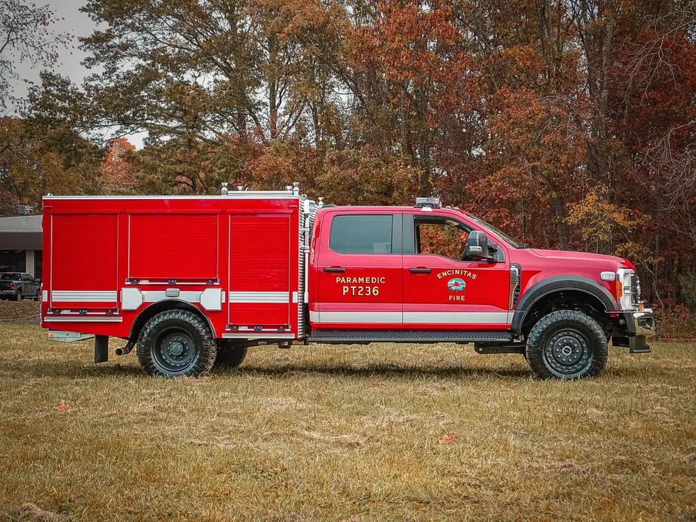 Driver-side profile of red brush truck with utility body.