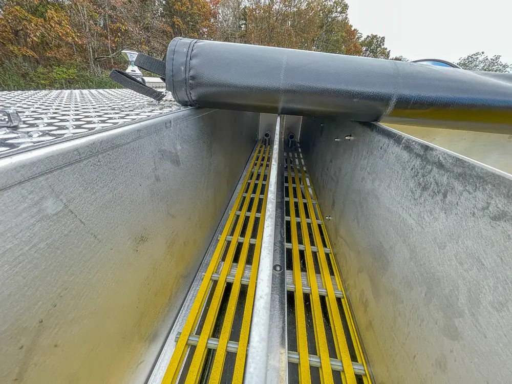 Close-up along yellow grated channel beneath rolled black cover.