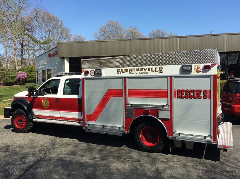Exterior view of small fire truck showing cab, body compartments, and wheel/tire area.