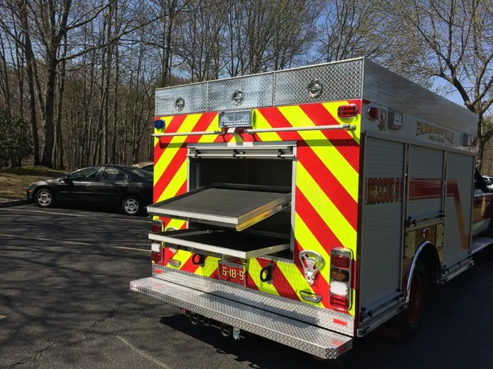 Exterior view of small fire truck showing cab, body compartments, and wheel/tire area.