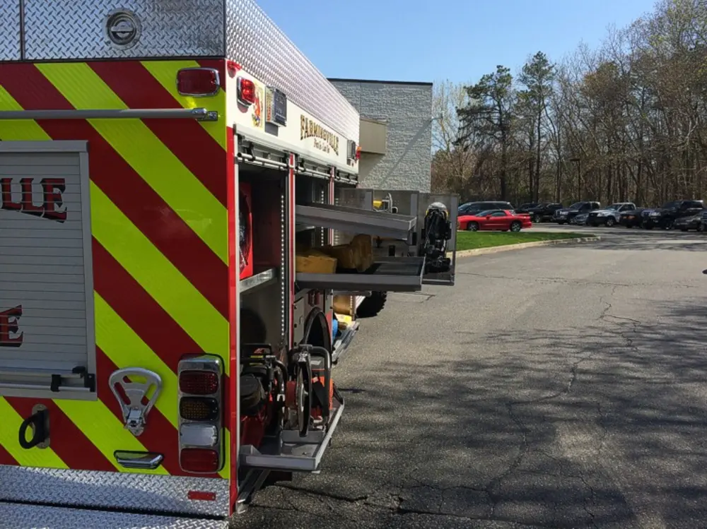 Exterior view of small fire truck showing cab, body compartments, and wheel/tire area.