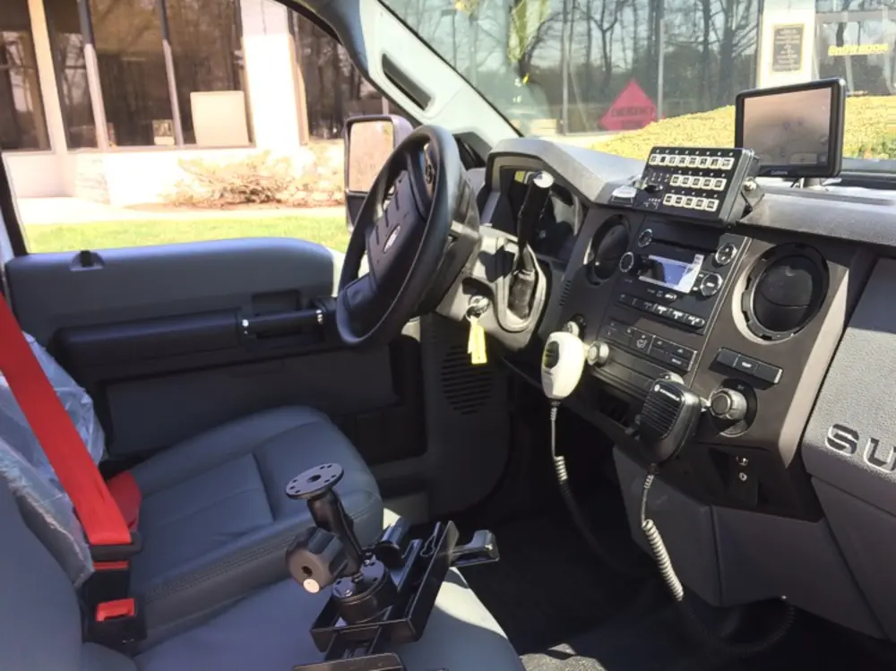 Exterior view of small fire truck showing cab, body compartments, and wheel/tire area.