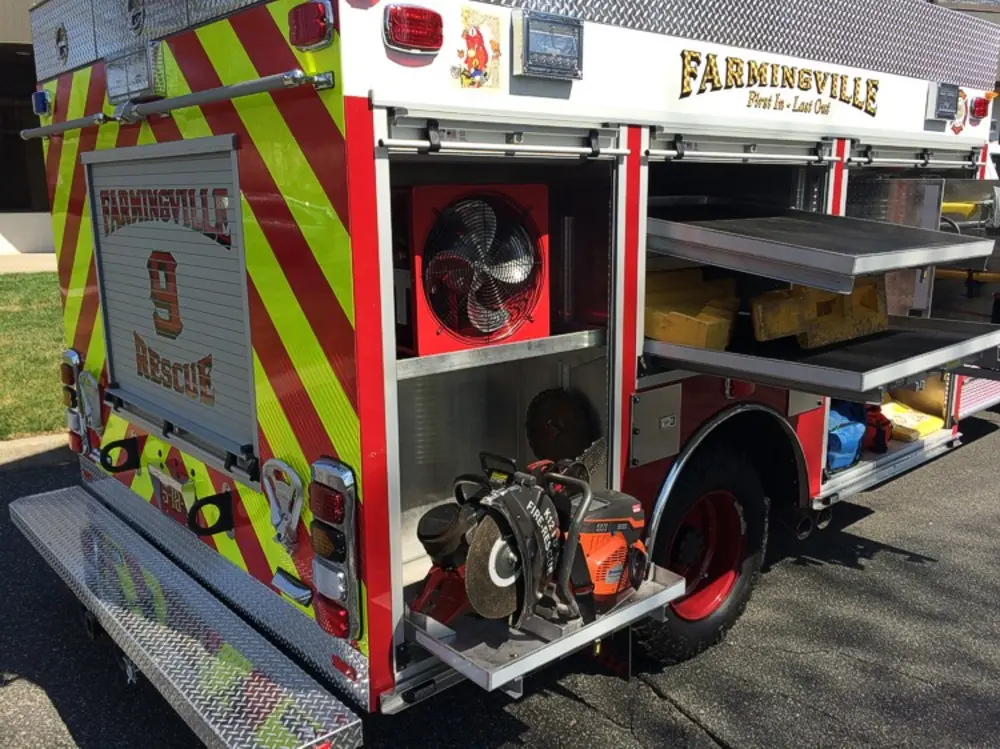 Exterior view of small fire truck showing cab, body compartments, and wheel/tire area.