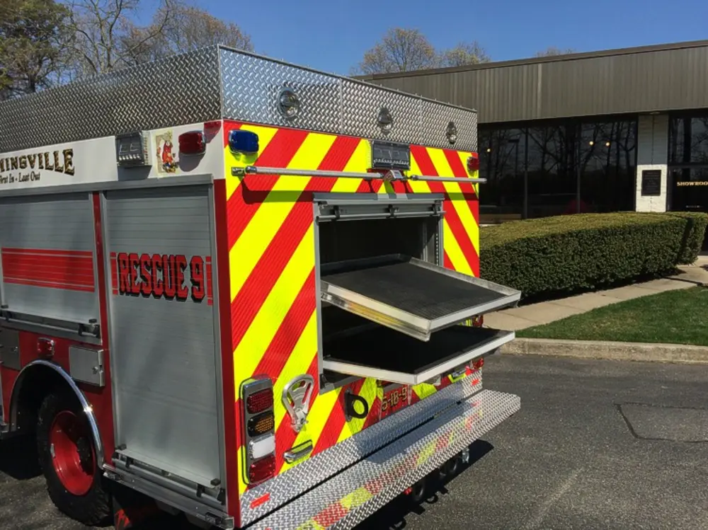 Exterior view of small fire truck showing cab, body compartments, and wheel/tire area.