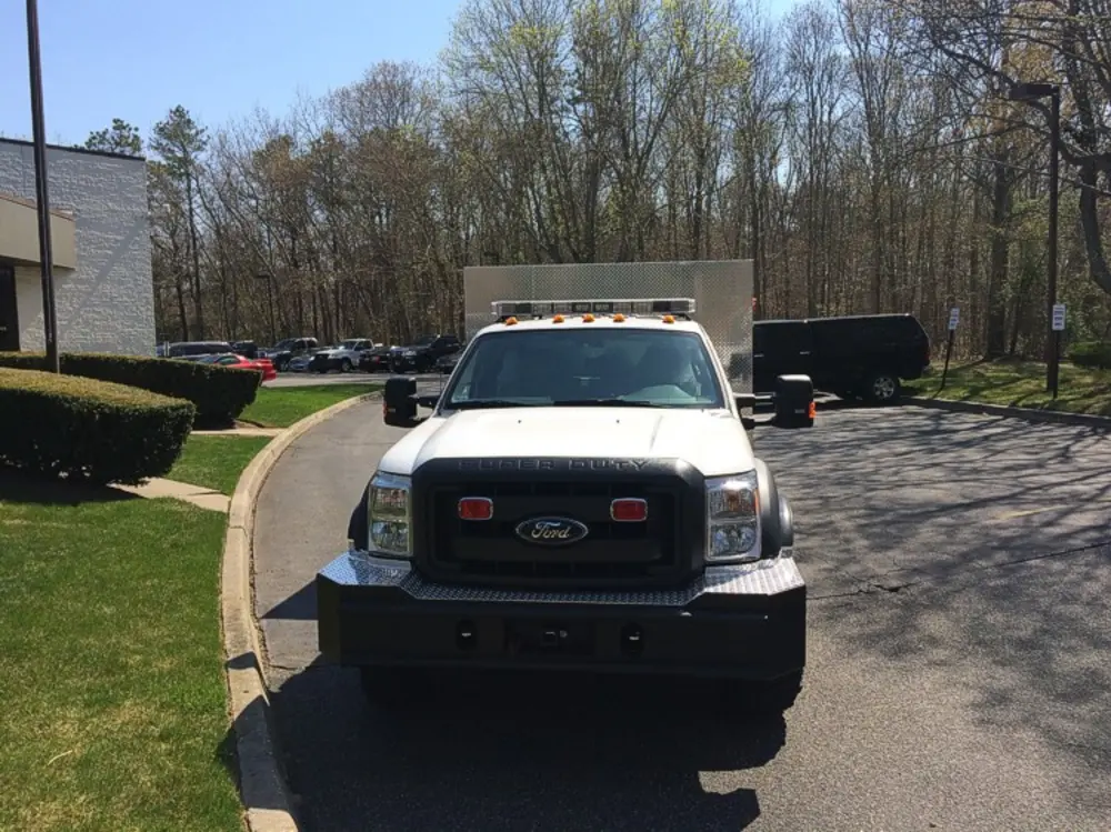 Exterior view of small fire truck showing cab, body compartments, and wheel/tire area.