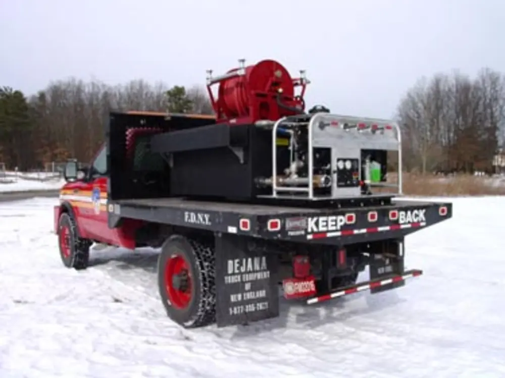 Exterior view of small fire truck showing cab, body compartments, and wheel/tire area.
