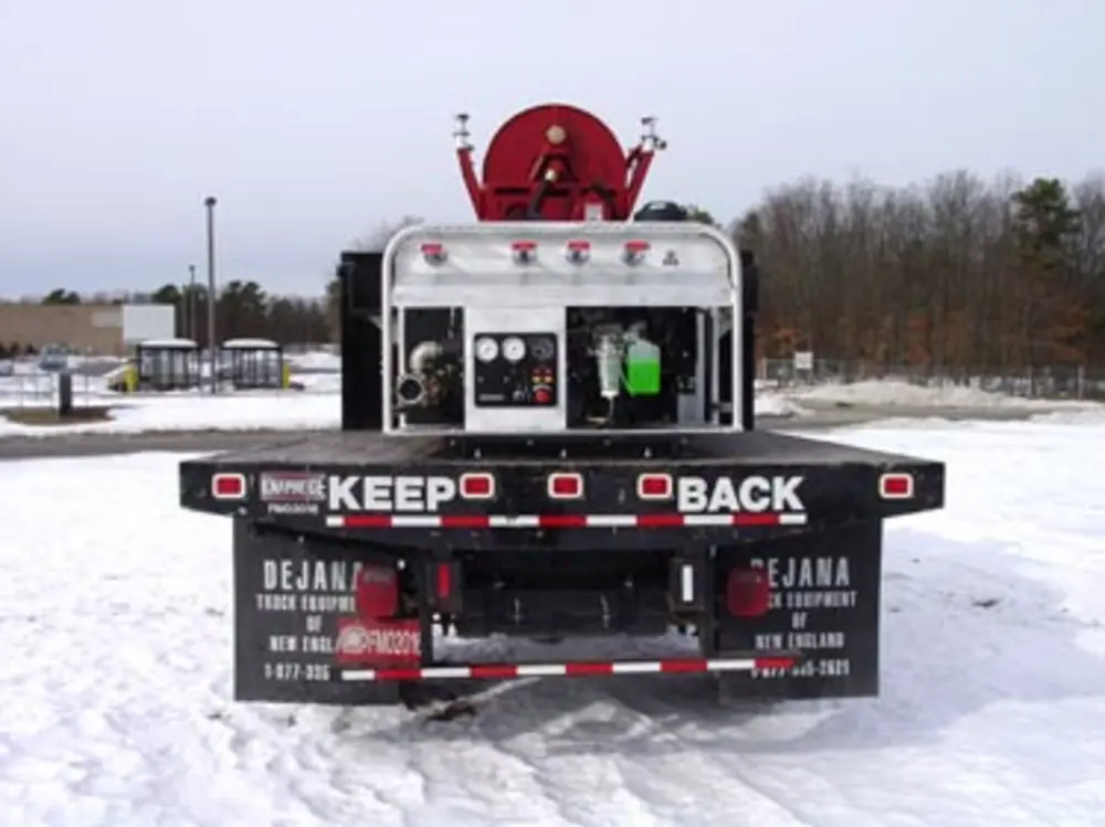 Exterior view of small fire truck showing cab, body compartments, and wheel/tire area.