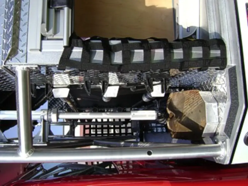 Exterior view of small fire truck showing cab, body compartments, and wheel/tire area.