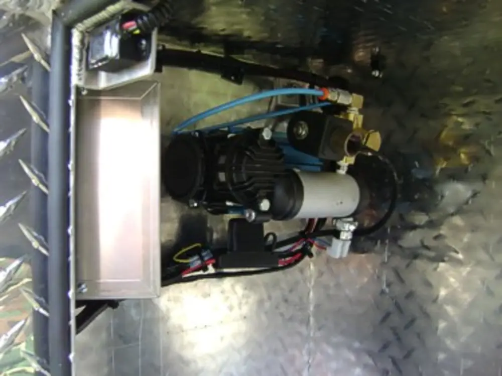 Exterior view of small fire truck showing cab, body compartments, and wheel/tire area.