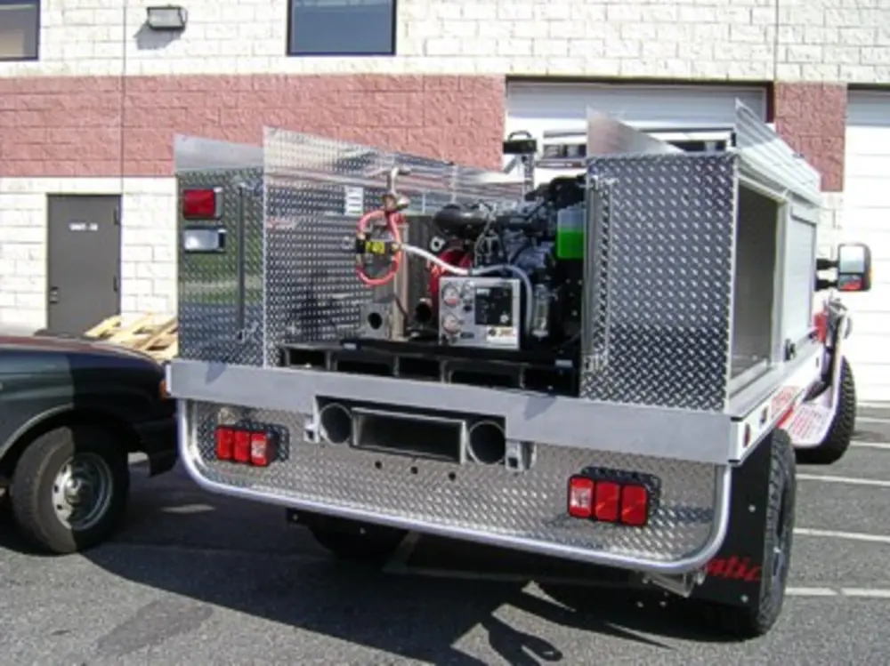 Exterior view of small fire truck showing cab, body compartments, and wheel/tire area.
