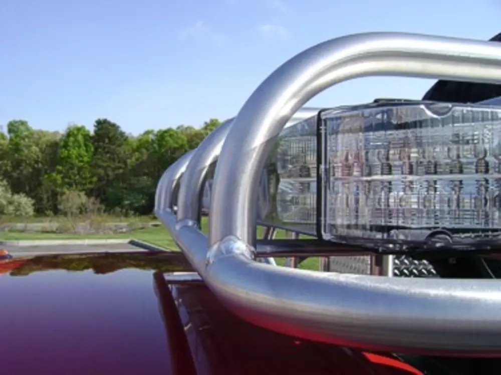 Exterior view of small fire truck showing cab, body compartments, and wheel/tire area.