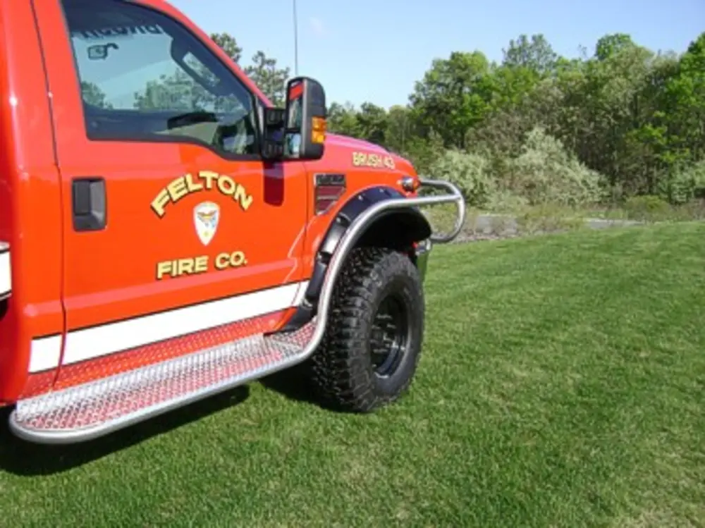Exterior view of small fire truck showing cab, body compartments, and wheel/tire area.