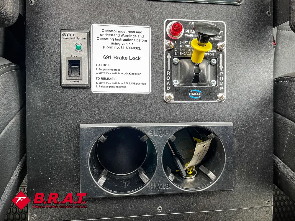 Dual cup holder panel with power outlets and small placard.