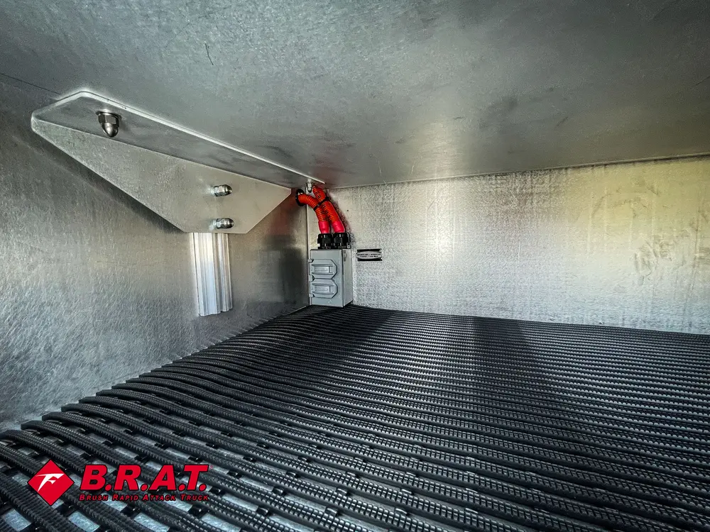 Empty aluminum compartment with black ribbed floor mat.