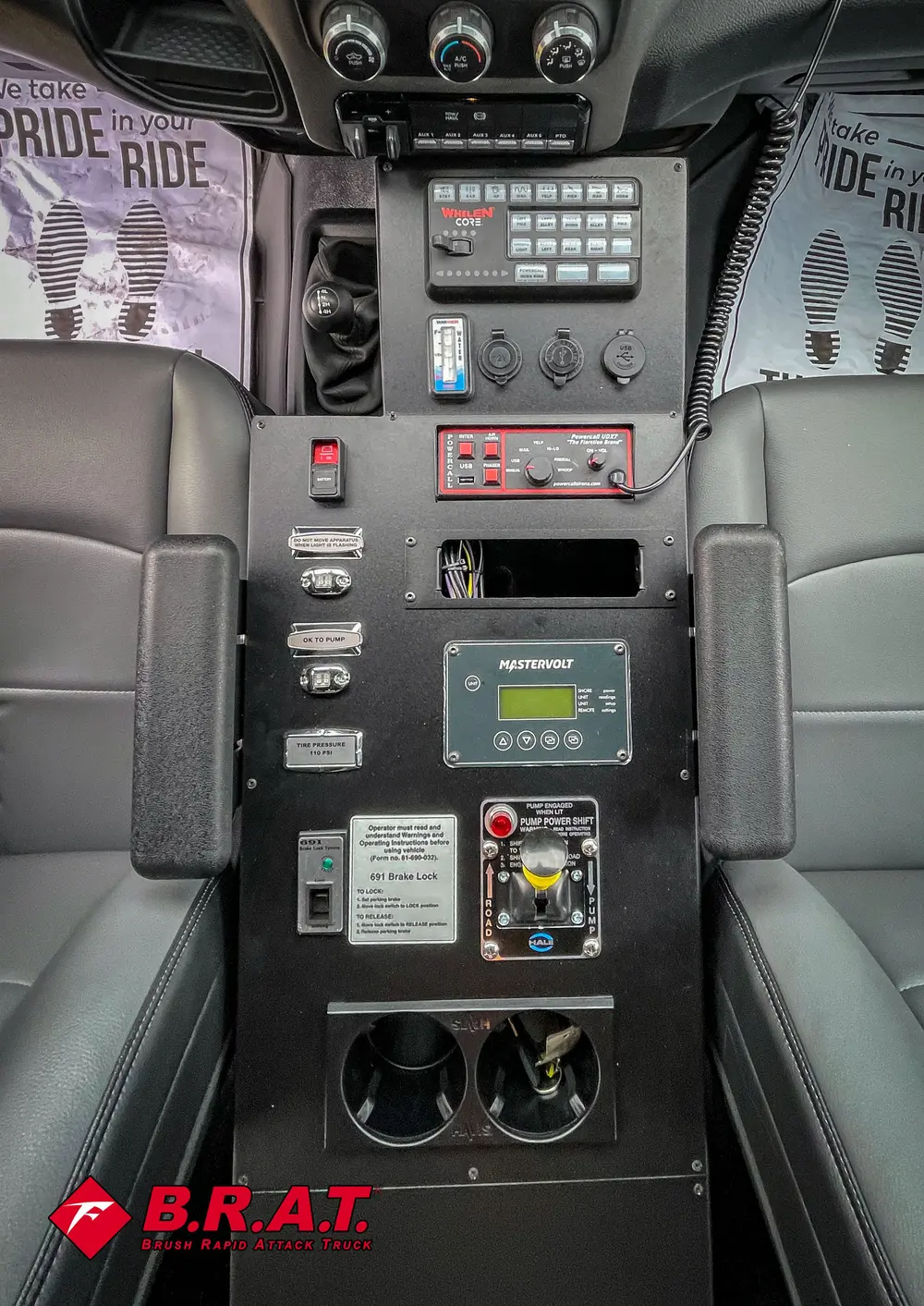Vertical control panel between seats with labeled switches and monitor.