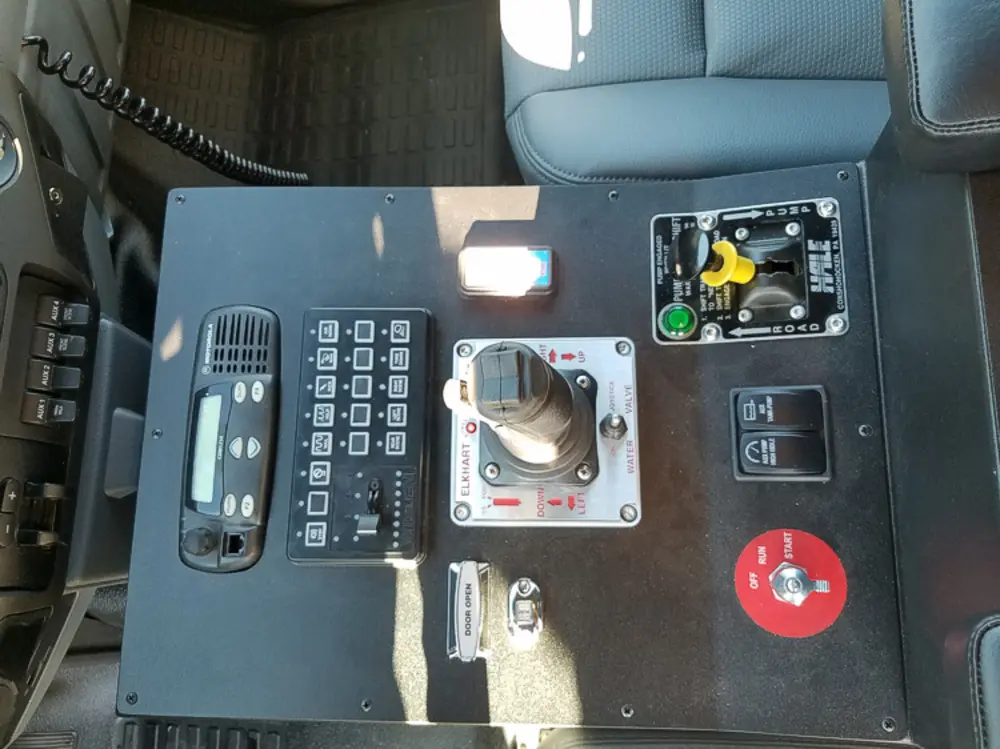 Exterior view of small fire truck showing cab, body compartments, and wheel/tire area.