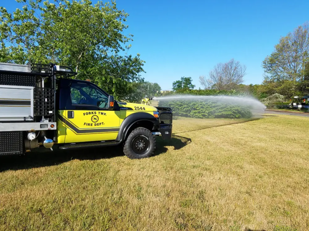 Exterior view of small fire truck showing cab, body compartments, and wheel/tire area.