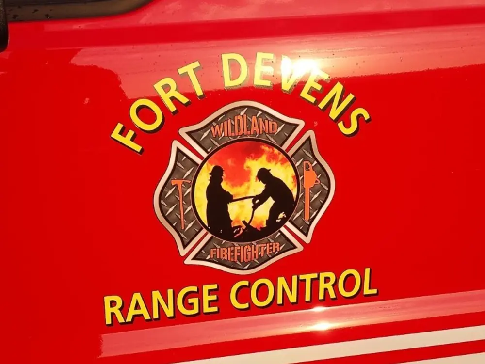 Exterior view of small fire truck showing cab, body compartments, and wheel/tire area.