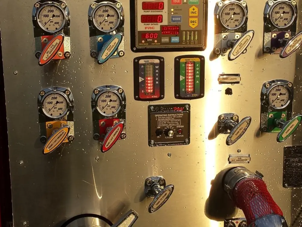 Exterior view of small fire truck showing cab, body compartments, and wheel/tire area.