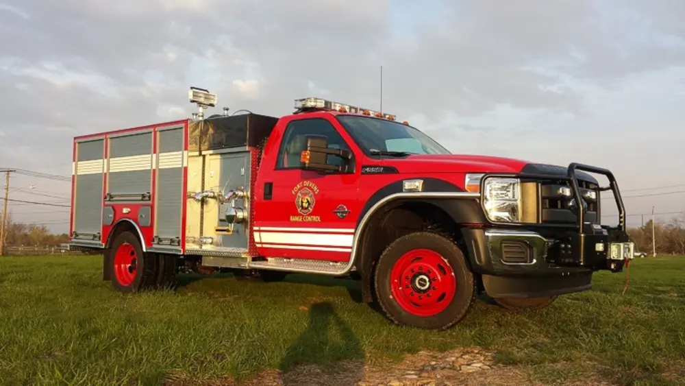 Exterior view of small fire truck showing cab, body compartments, and wheel/tire area.