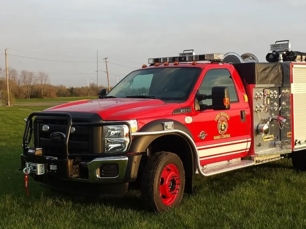 Exterior view of small fire truck showing cab, body compartments, and wheel/tire area.