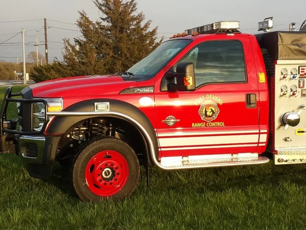 Exterior view of small fire truck showing cab, body compartments, and wheel/tire area.