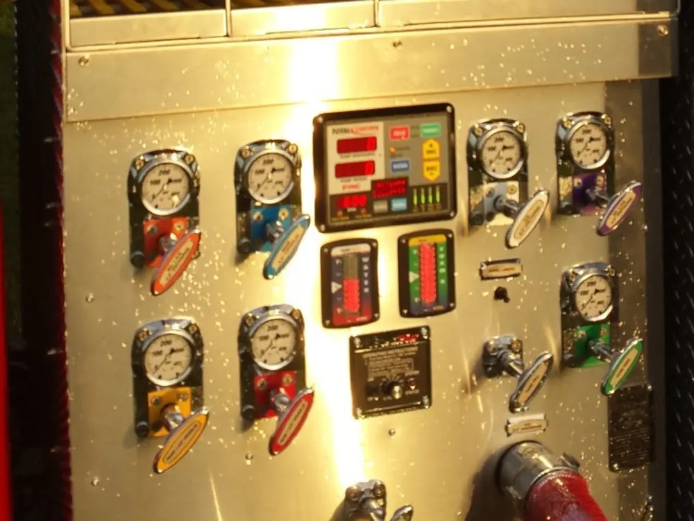 Exterior view of small fire truck showing cab, body compartments, and wheel/tire area.