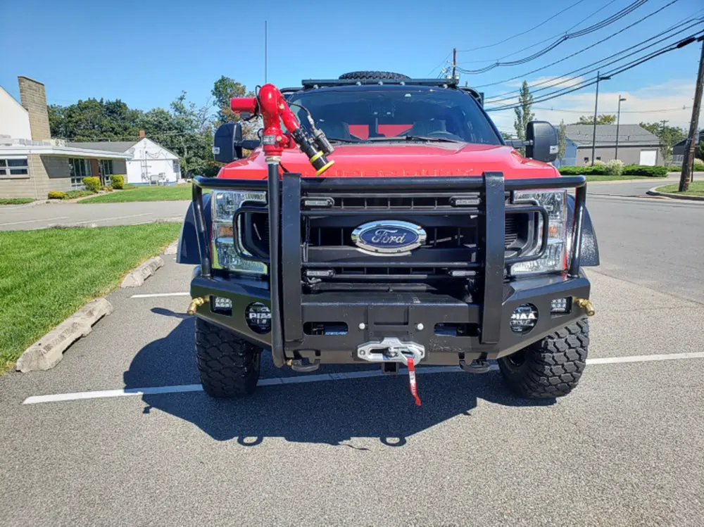 Exterior view of small fire truck showing cab, body compartments, and wheel/tire area.