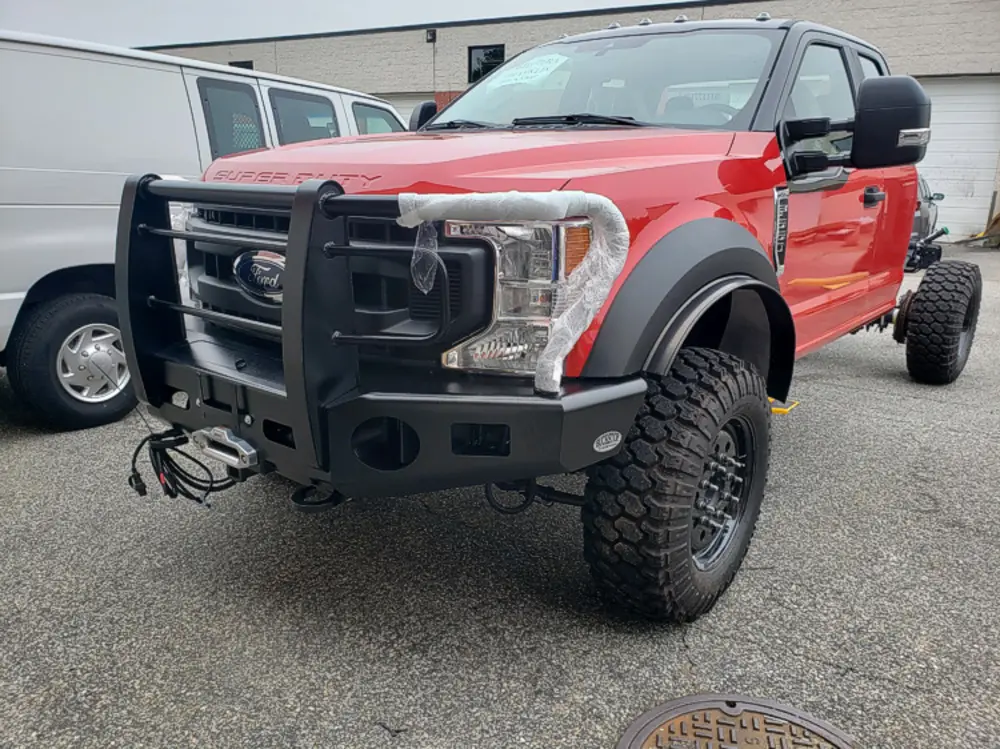 Exterior view of small fire truck showing cab, body compartments, and wheel/tire area.