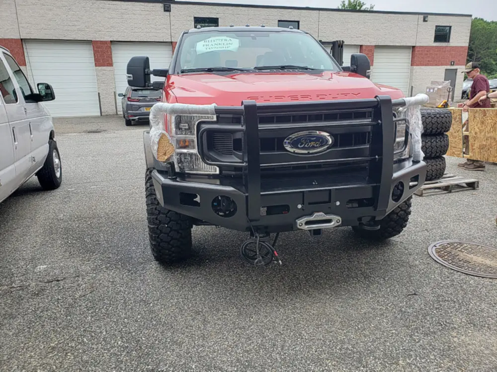 Exterior view of small fire truck showing cab, body compartments, and wheel/tire area.