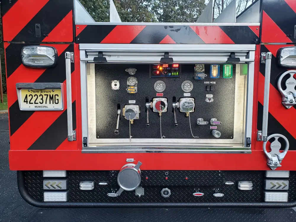 Exterior view of small fire truck showing cab, body compartments, and wheel/tire area.