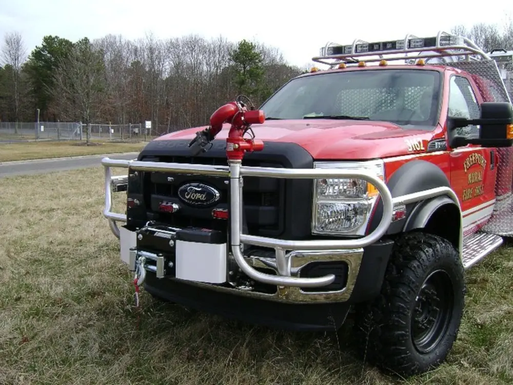 Exterior view of small fire truck showing cab, body compartments, and wheel/tire area.