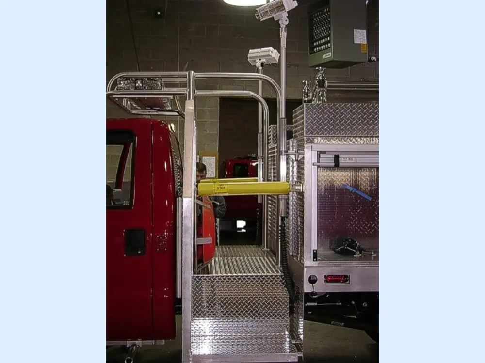 Exterior view of small fire truck showing cab, body compartments, and wheel/tire area.
