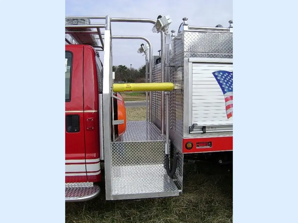 Exterior view of small fire truck showing cab, body compartments, and wheel/tire area.