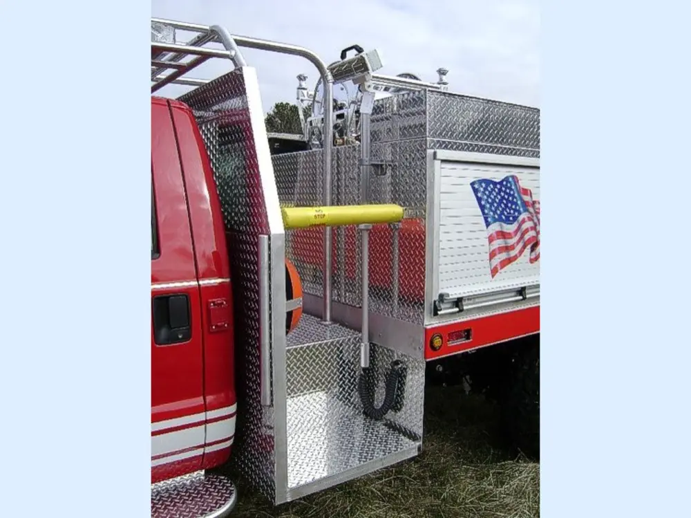 Exterior view of small fire truck showing cab, body compartments, and wheel/tire area.