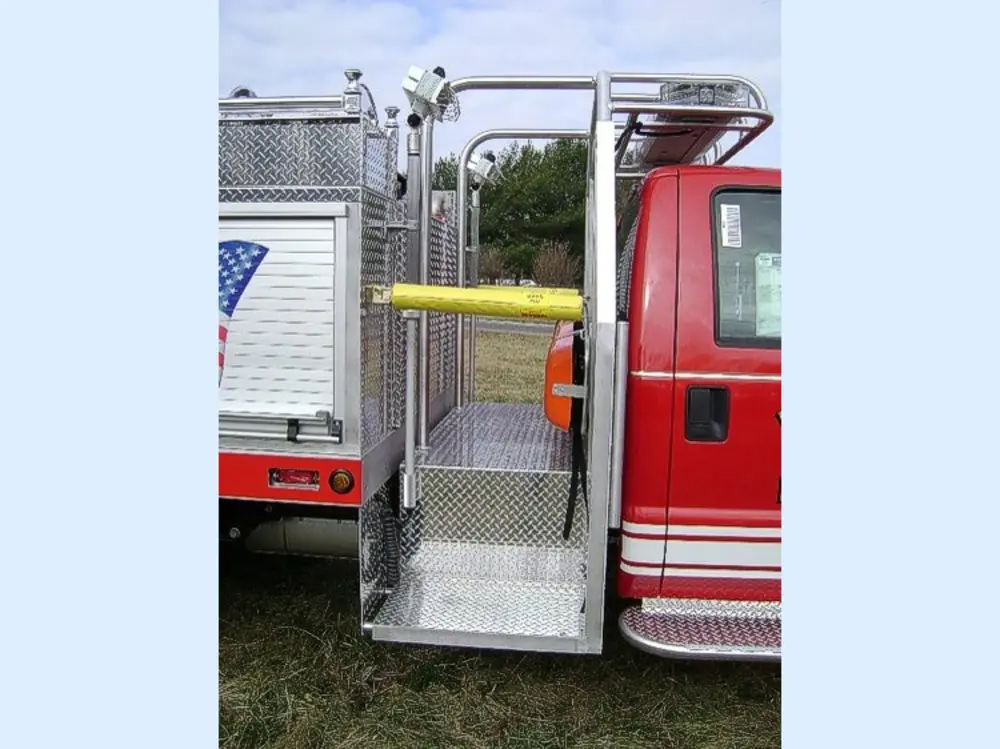 Exterior view of small fire truck showing cab, body compartments, and wheel/tire area.