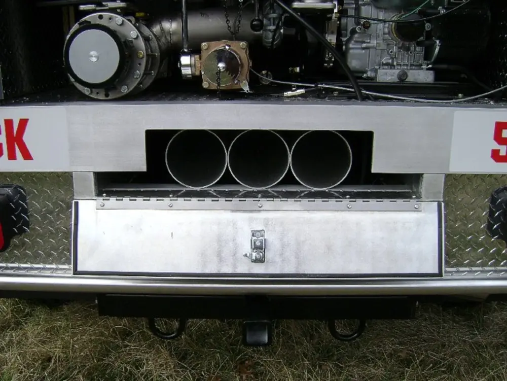 Exterior view of small fire truck showing cab, body compartments, and wheel/tire area.