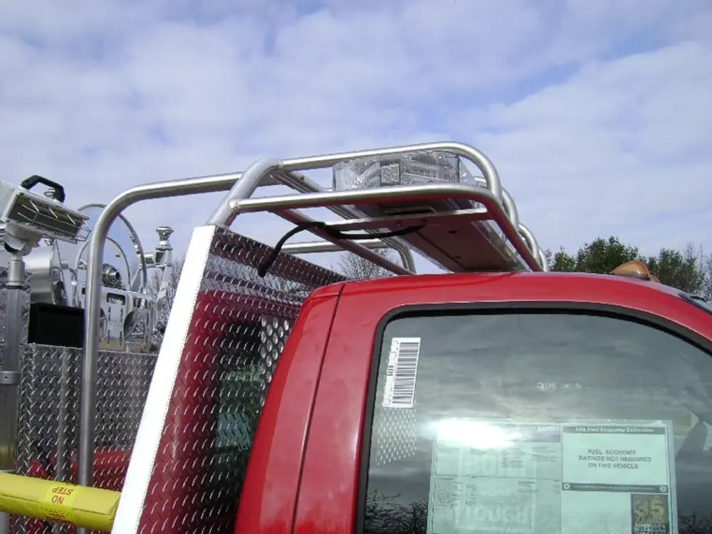 Exterior view of small fire truck showing cab, body compartments, and wheel/tire area.