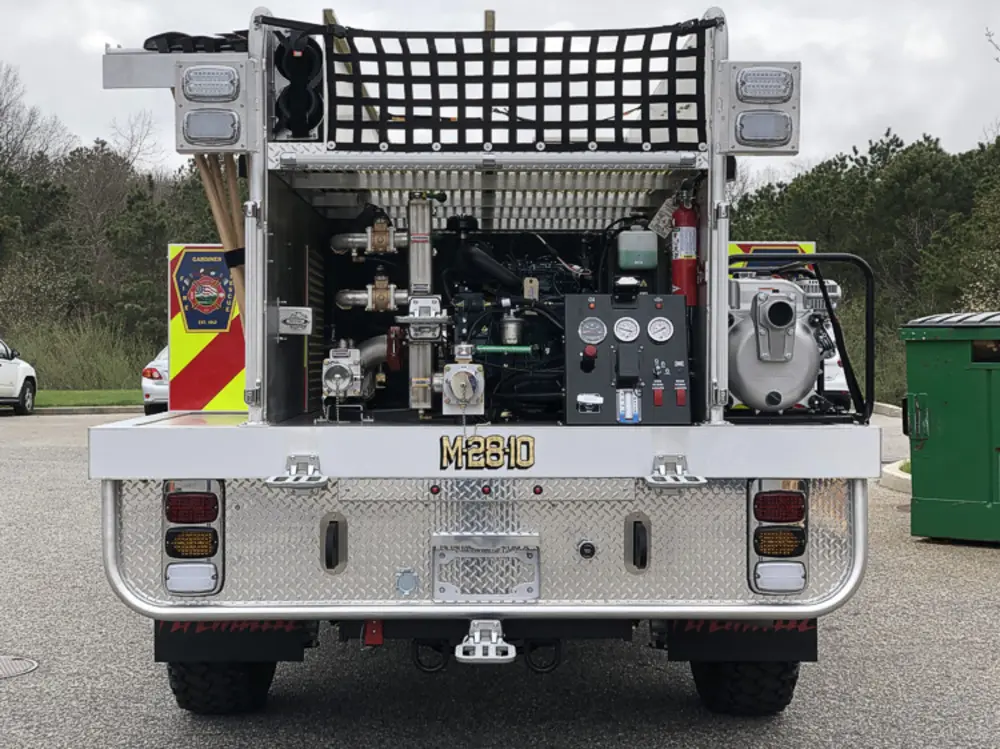 Exterior view of small fire truck showing cab, body compartments, and wheel/tire area.
