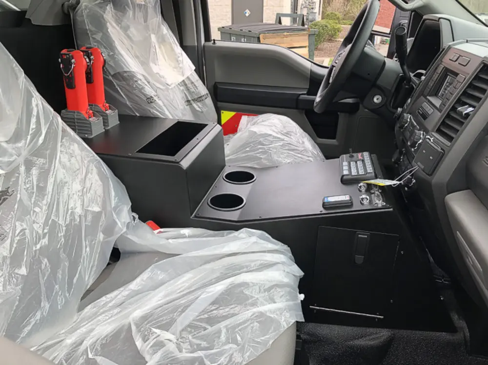 Exterior view of small fire truck showing cab, body compartments, and wheel/tire area.