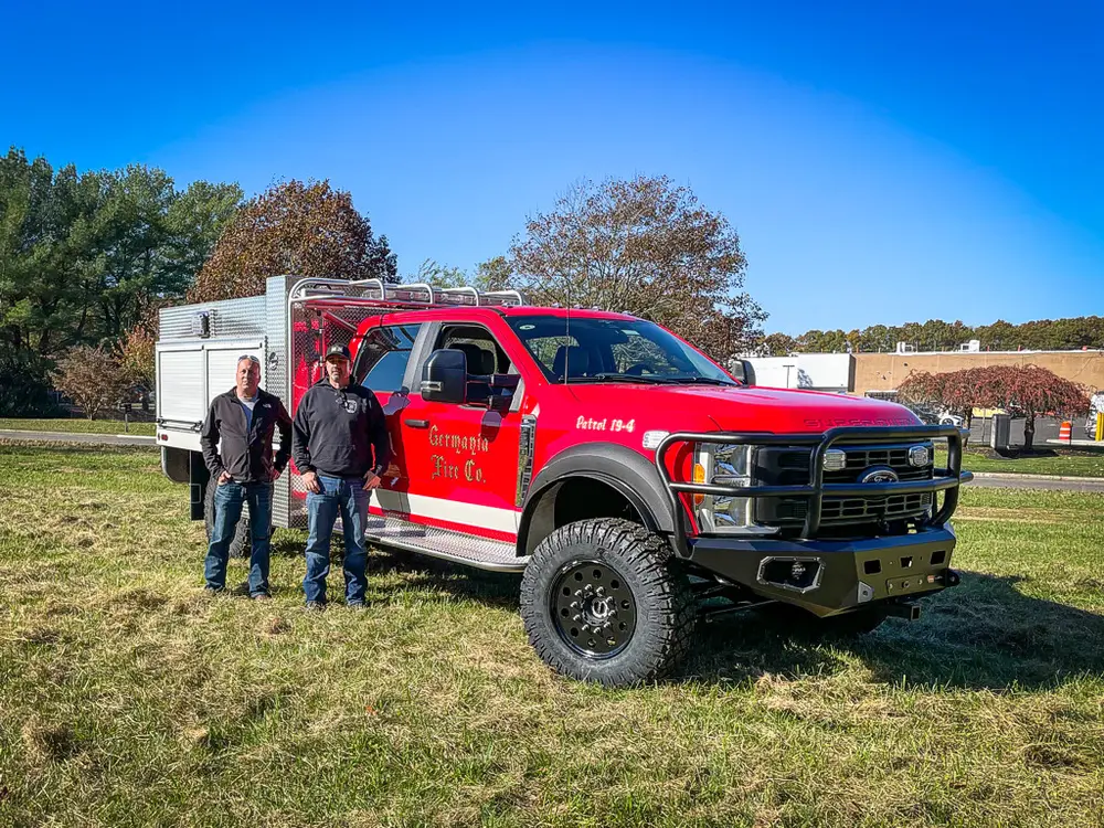 Two people standing beside the truck at front-left corner.